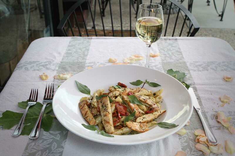 Penne pasta with grilled chicken and a glass of white wine